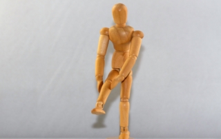 wooden figure positioned to look like it's holding up its leg