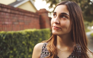 woman smiling while standing outside and looking up towards the sky