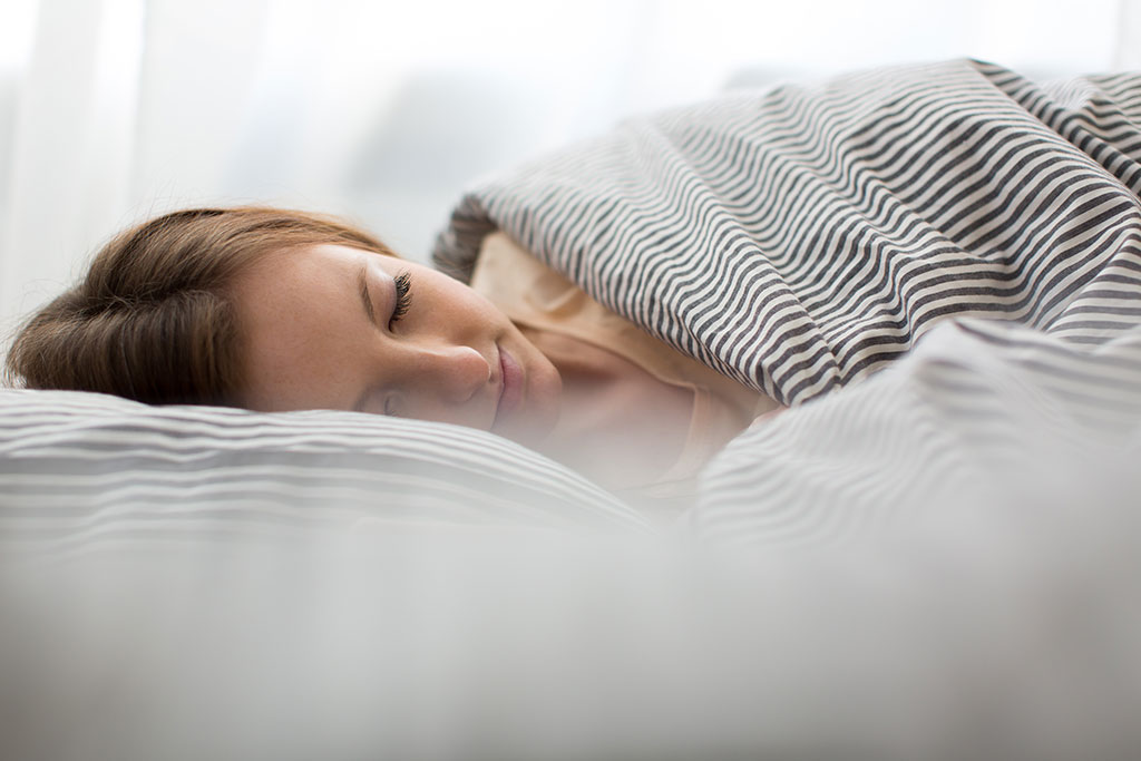 woman sleeping soundly in her bed while experiencing sleep benefits