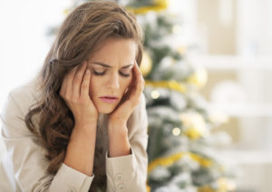woman massaging her head trying to manage holiday stress