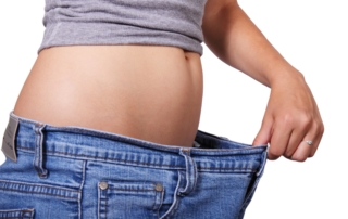 woman holding her pants out from her waist experiencing weight loss