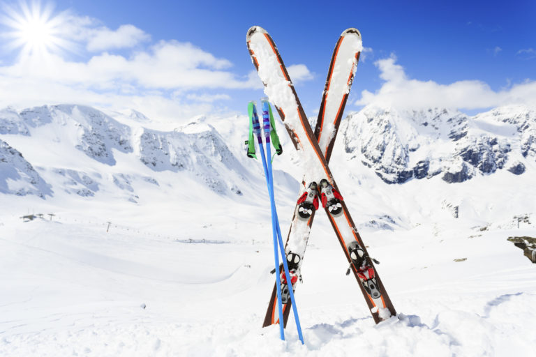 pair of skis positioned upward in the show with large mountainous range behind them
