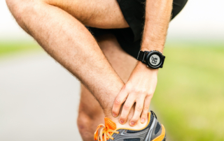 closeup of a runner holding his ankle mid run due to pain