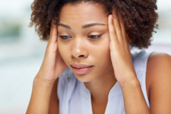 closeup of woman holding her hands up to her head with a stressed look on her face