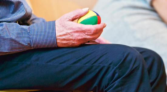 closeup of man holding a colorful ball during physical therapy