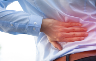 man holding hand up against back experiencing back pain