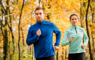 man and woman jogging in yellow foliage forest