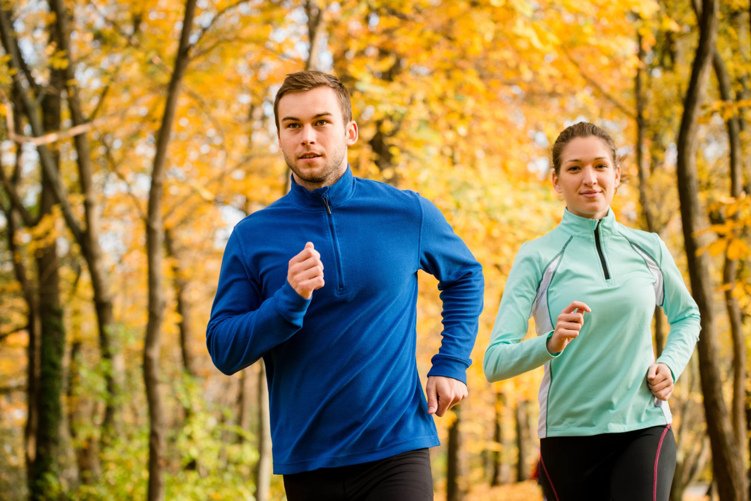 man and woman jogging in yellow foliage forest