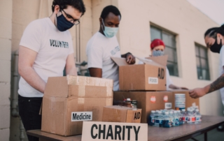 volunteers for the 2021 Shoebox Project wearing masks and volunteer shirts with boxes surrounding them