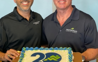 two men with a cake for Momentum Physical Therapy's anniversary