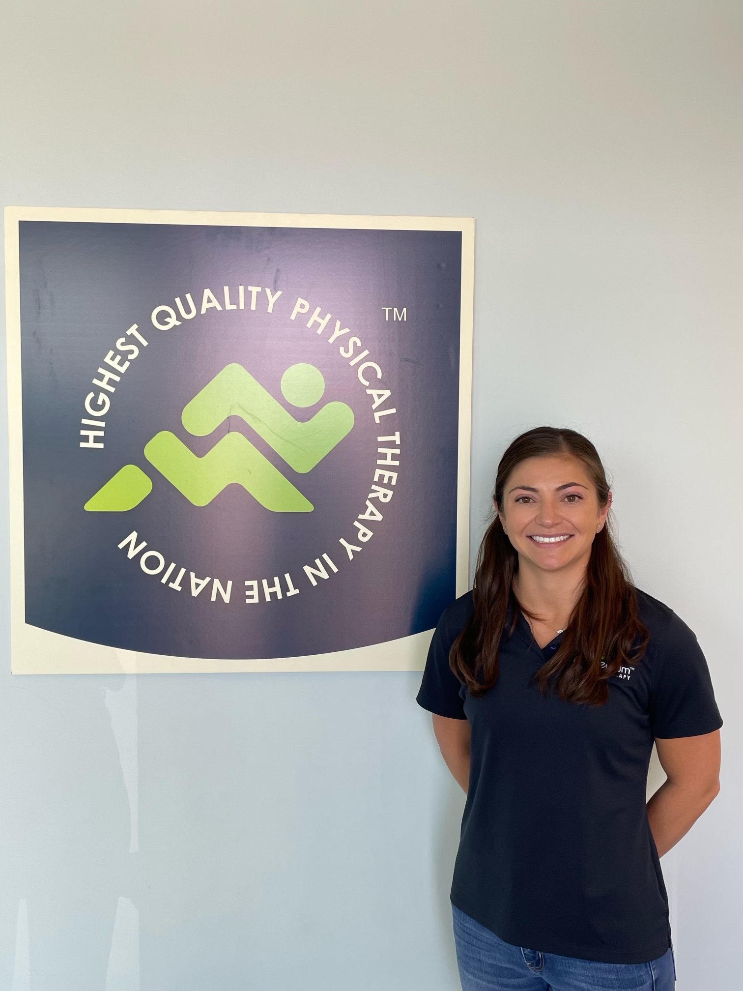 Gina Martinez in front of a sign for Momentum Physical Therapy
