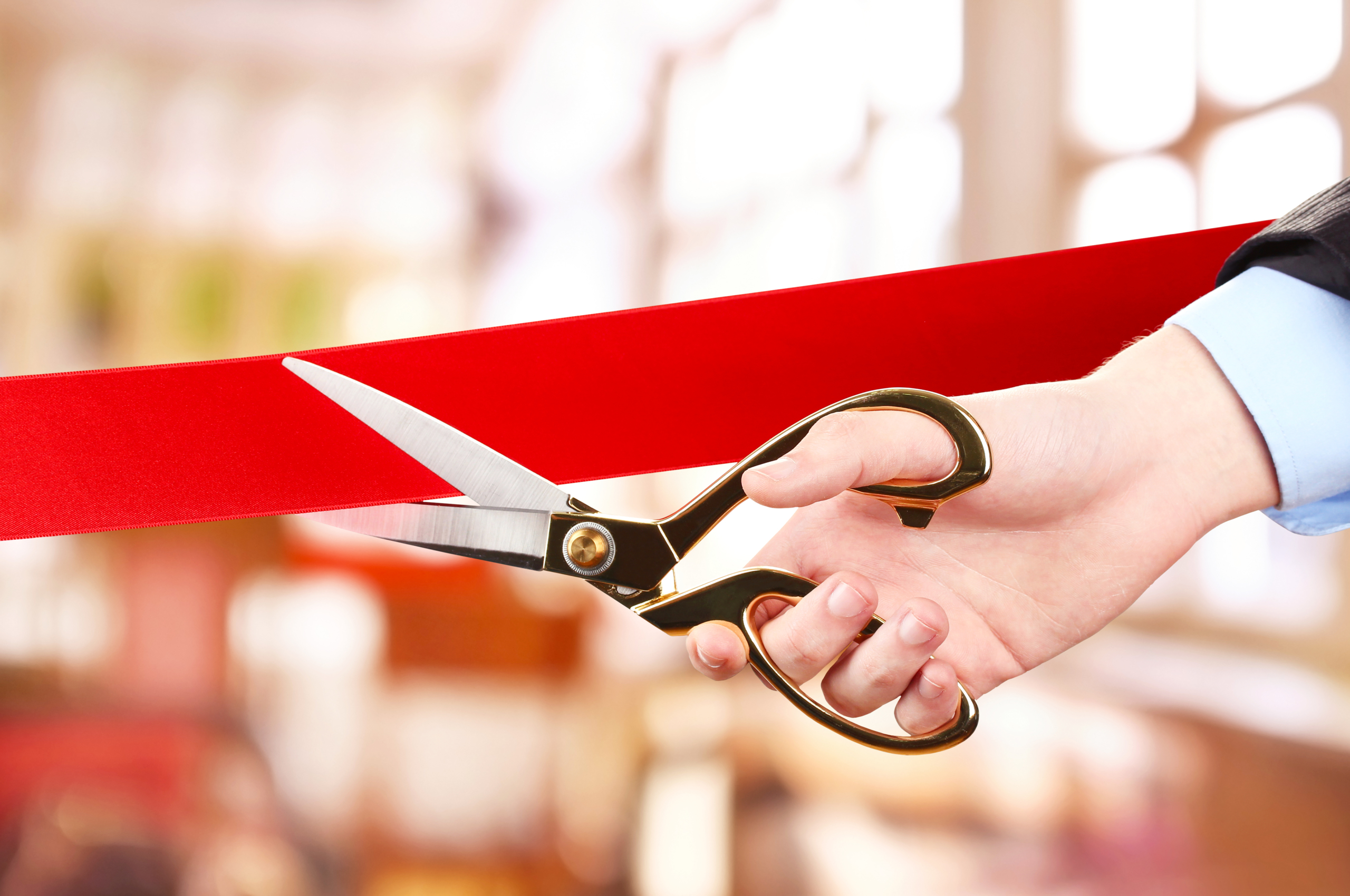 hand cutting red ribbon with scissors